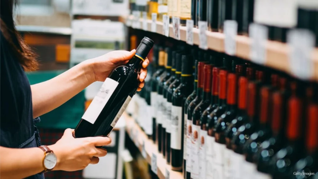 Cliente escolhendo uma garrafa de vinho em uma loja especializada.