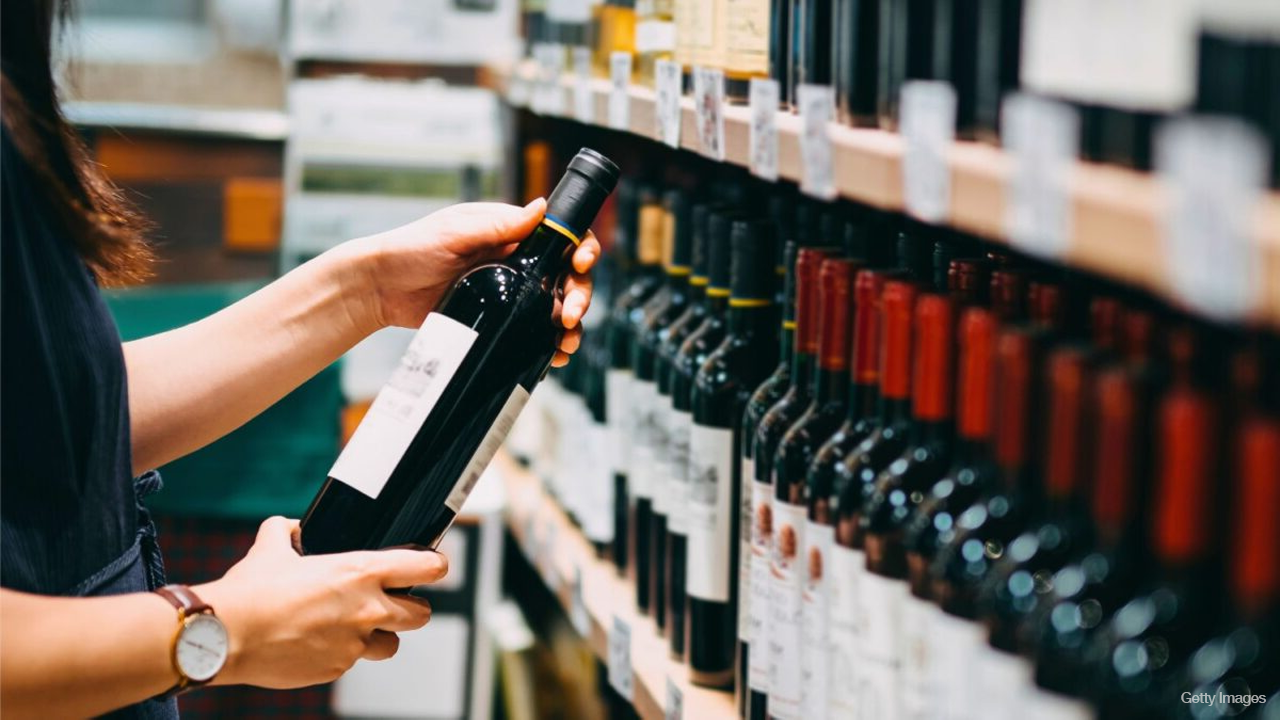 Cliente escolhendo uma garrafa de vinho em uma loja especializada.